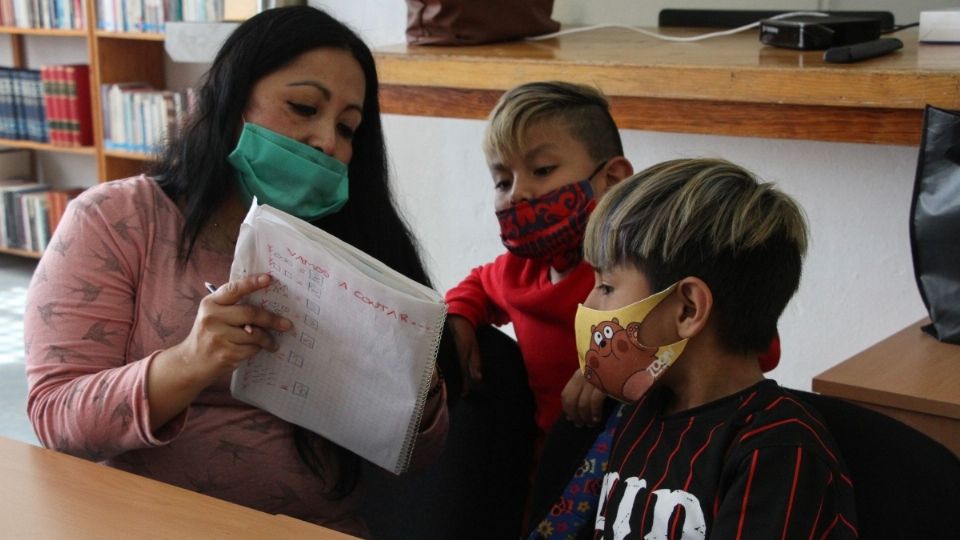 Maestra asesora a dos niños en el Club de Tareas de la alcaldía Magdalena Contreras. FOTO: ROGELIO MORALES /CUARTOSCURO.COM