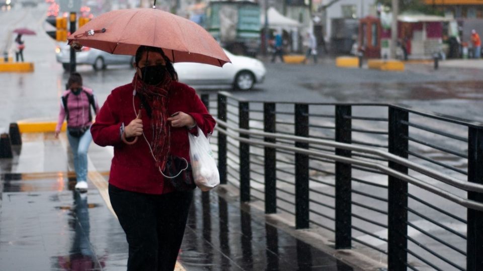 Una mujer camina rumbo a la estación Centro Médico bajo la lluvia. FOTO: DANIEL AUGUSTO/CUARTOSCURO.COM