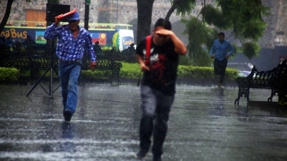 Hombres corren para protegerse de la lluvia, FOTO: CUARTOSCURO