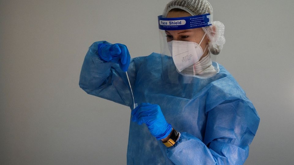 Personal médico sostiene una prueba de Covid-19 previamente realizada. Foto: AFP