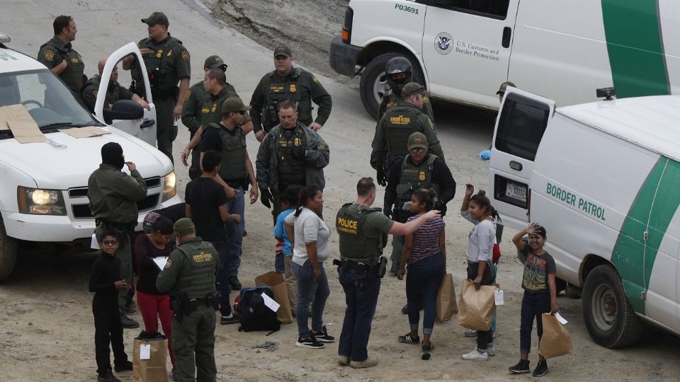 Migrantes y agentes de la patrulla fronteriza en la frontera de San Diego, California. Foto: AP