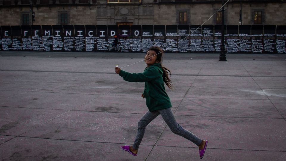 La niña sonríe con su papalote, a unos metros de las vallas. Foto: Cuartoscuro