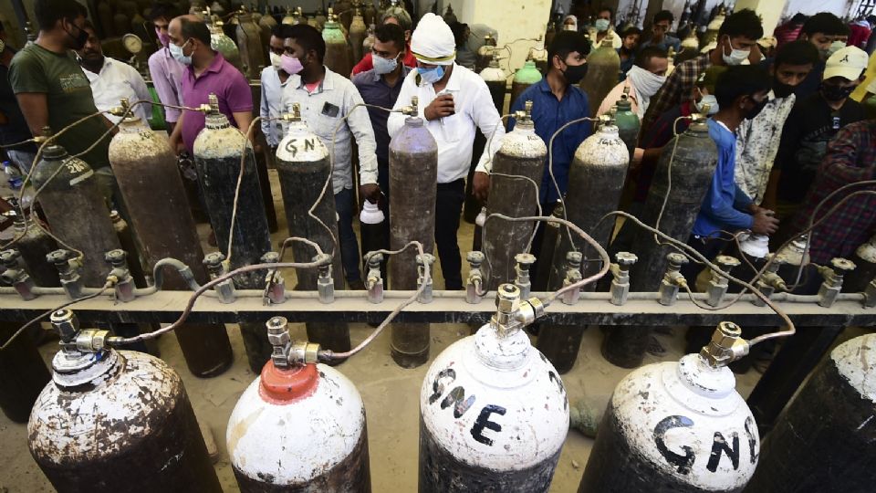 EN INDIA. Personas rellenan cilindros de oxigeno para pacientes COVID. Foto: AFP