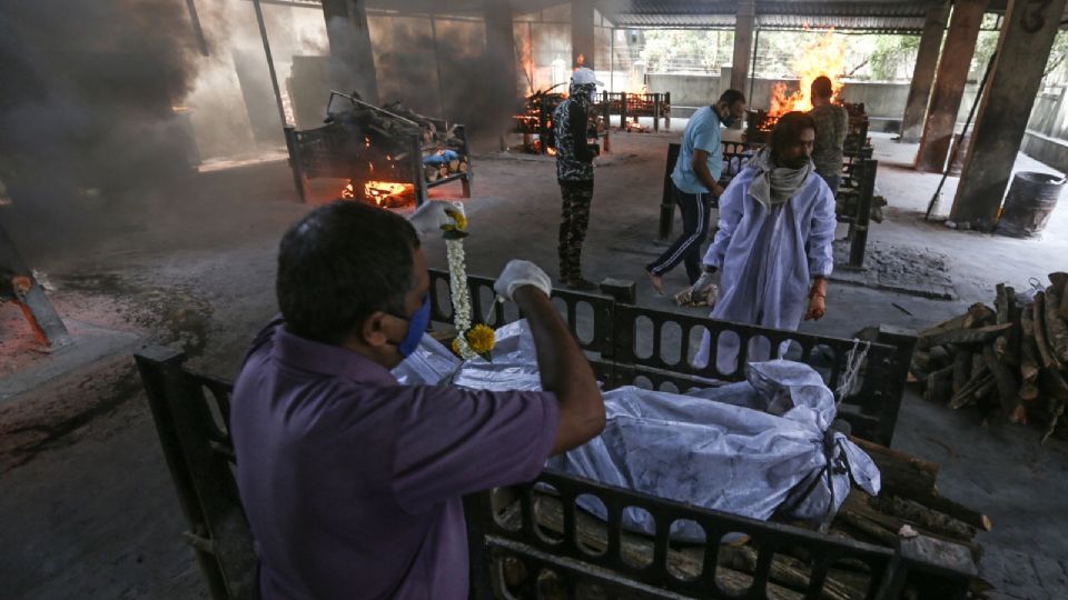 Trabajadores realizan los últimos ritos para las víctimas del COVID-19.  Foto: EFE