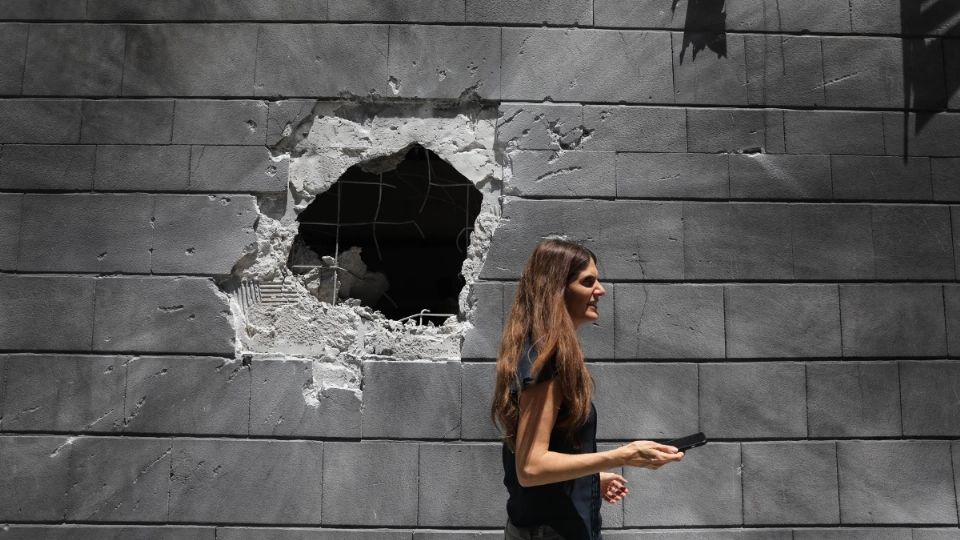 Una mujer pasa ante un edificio dañado en un bombardeo en la ciudad israelí de Ashkelon el pasado viernes. Foto: EFE