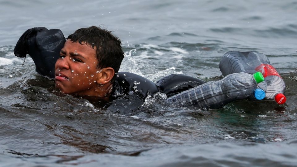 Niño marroquí nada a Ceuta usando botellas de plástico para flotar. Foto: Reuters