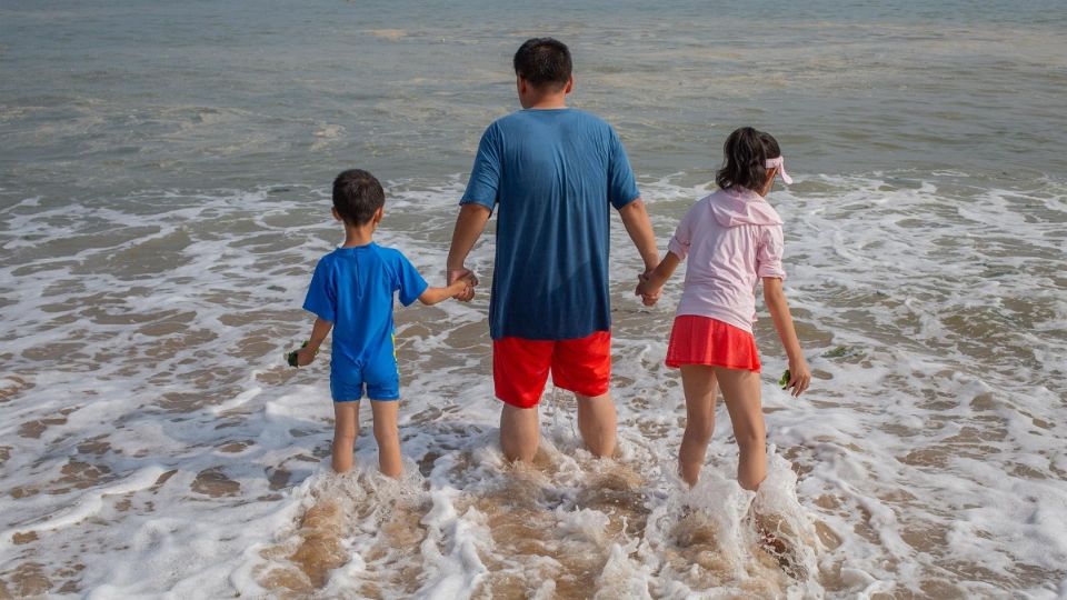 Padre pasea junto a sus hijos por la playa. Foto: Especial