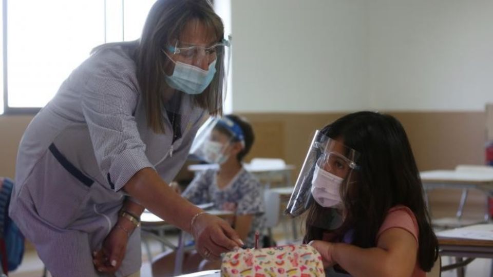 Docente atiende a alumna en aula de clase con todas las medidas sanitarias. Foto: Especial