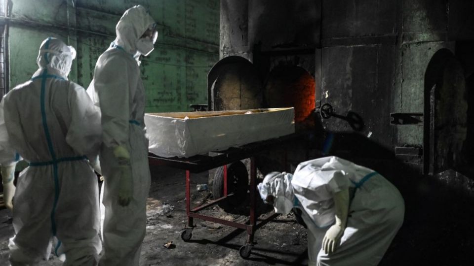 Voluntarios se protegen bien y transportan los cadáveres hasta los crematorios. Foto: AFP