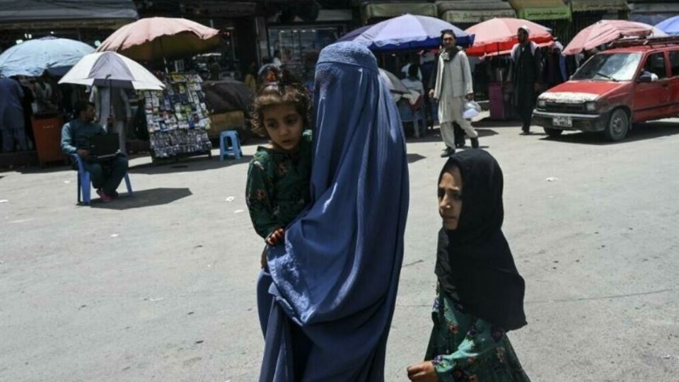 Mujer camna junto a sus hijos en calles de Afganistán. Foto: AFP