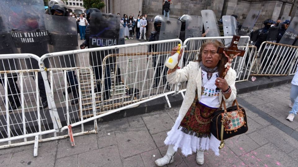 Mujer arroja agua bendita a feministas durante marcha en Toluca. Foto: Cuartoscuro