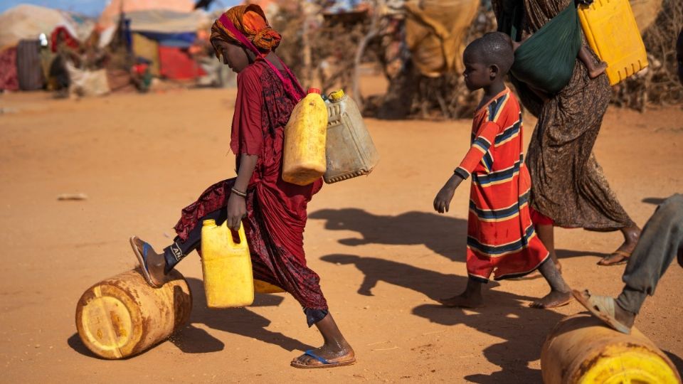 SOMALIA. Una mujer y niños cargaban agua en un campamento para personas desplazadas