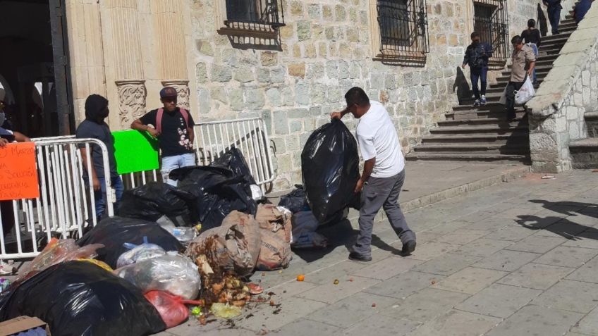 Trabajadores de limpia arrojan bolsas de basura en Palacio Municipal de Oaxaca de Juárez