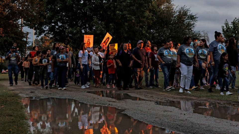 Las personas sostienen fotografías de Eliahna Torres mientras desfilan en un gran grupo por el cementerio Hillcrest Memorial en Uvalde.