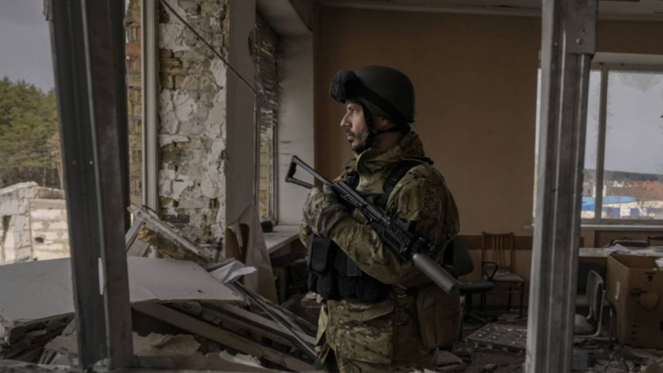 Un militar observa desde el interior de un edificio en ruinas en Mariúpol