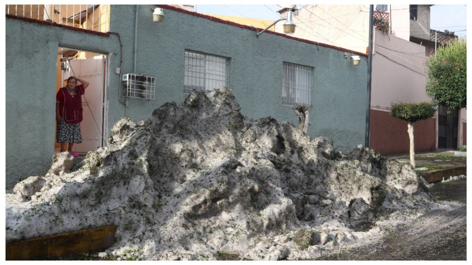 Montaña de granizo cubre la entrada de una casa.