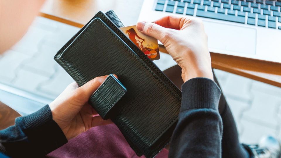 Mujer saca de su cartera una tarjeta para pagar un producto.