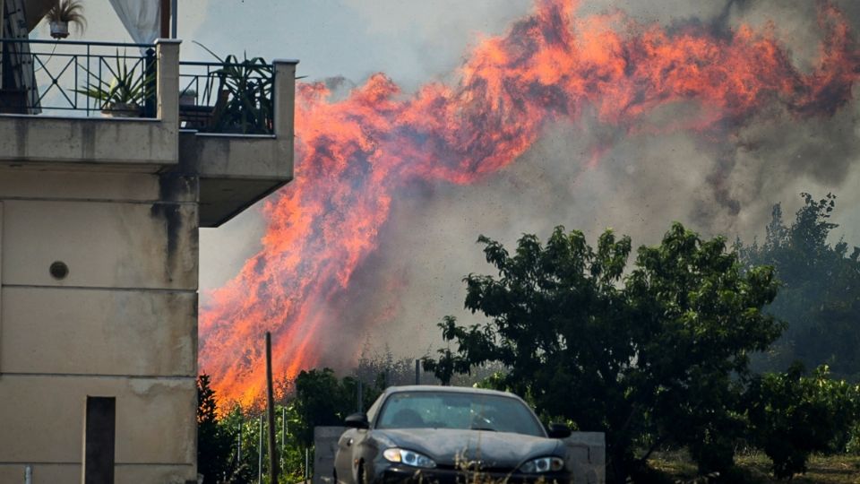 Las llamas se elevaban ayer cerca de una casa, mientras un incendio forestal ardía en el pueblo de Krestena, en Grecia