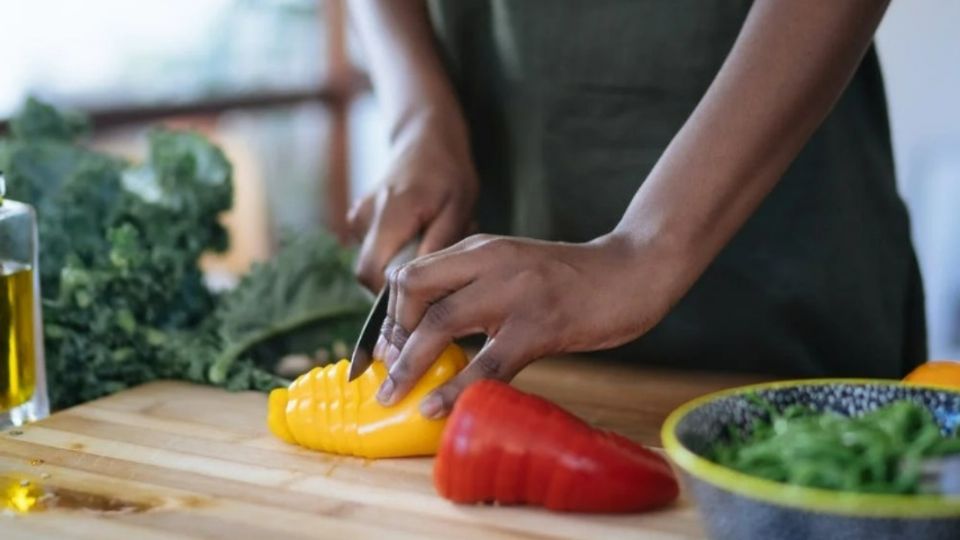 Imagen ilustrativa de mujer cortando vegetales.