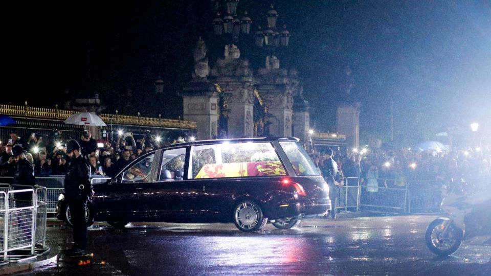 Los policías inclinan la cabeza mientras el coche fúnebre que lleva el ataúd de la reina Isabel II de Gran Bretaña se dirige al Palacio de Buckingham.