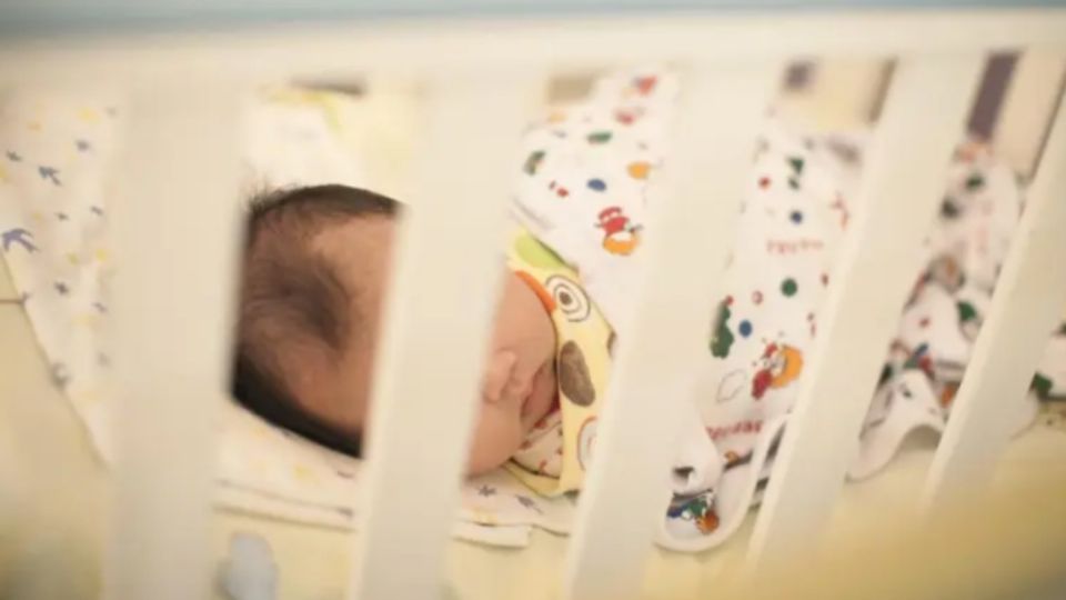 Un bebé descansa en su cuna.