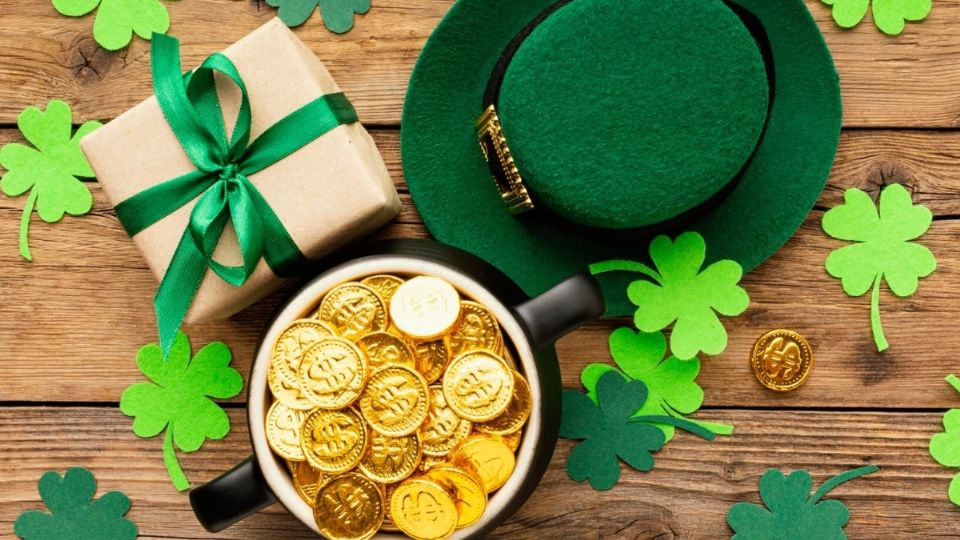 Una vasija con monedas de oro, un regalo y un sombrero verde de la suerte.