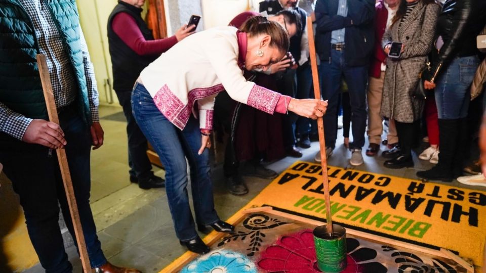 Claudia Sheinbaum realizando un tapete de aserrín.