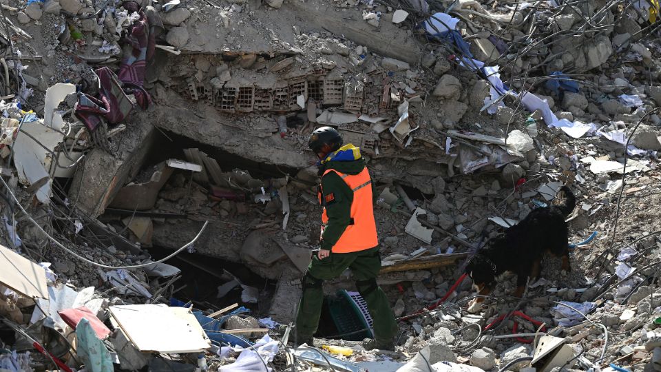 Un perro de búsqueda y rescate y su amo buscan entre los escombros de los edificios derrumbados en Kahramanmaras el 14 de febrero de 2023.