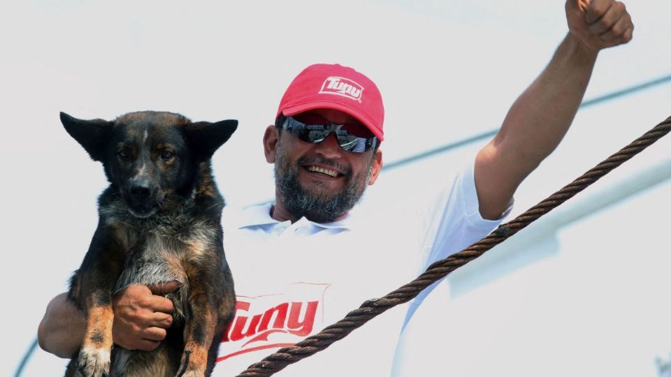 Un miembro de la tripulación del buque atunero mexicano 'Maria Delia' posa para una foto con 'Bella', la perra del marinero australiano Tim Shaddock.