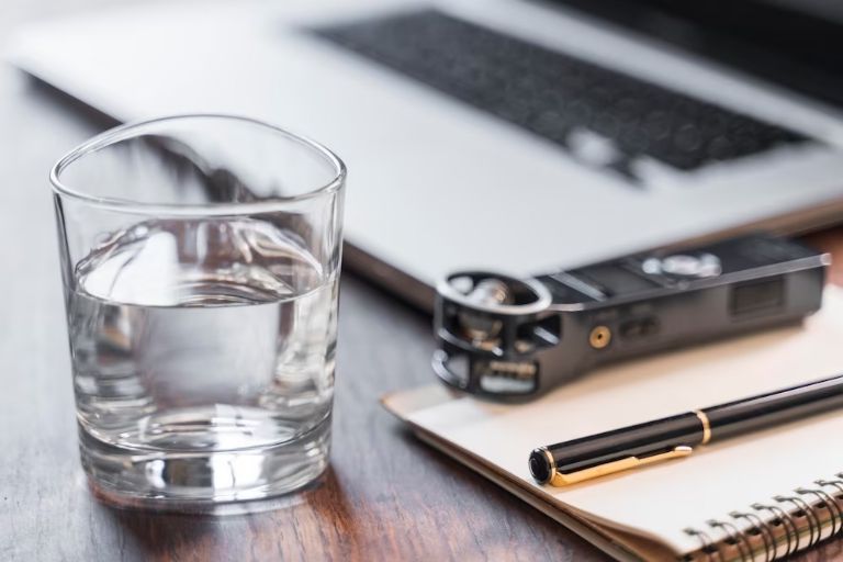 vaso de agua sobre una mesa de luz en la habitacion