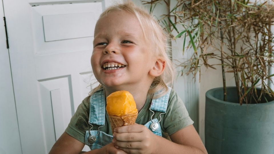 Una niña disfruta de su helado y es feliz al comerlo, algo que es un beneficio