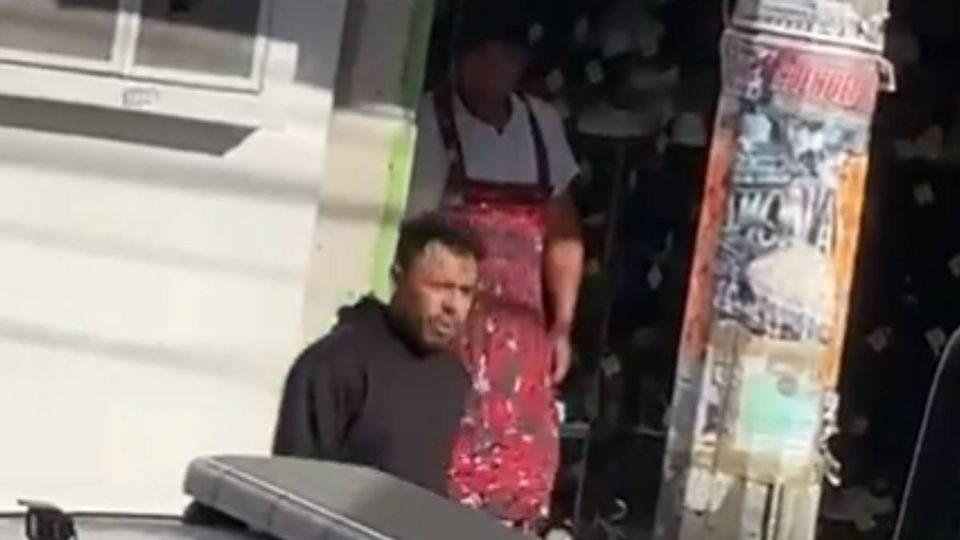 El sujeto saliendo de un local comercial con un cuchillo en mano