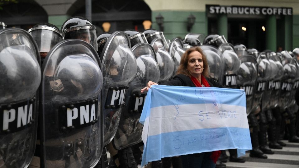 Mujer sostienen la bandera de Argentina durante enfrentamiento contra policías en el Congreso