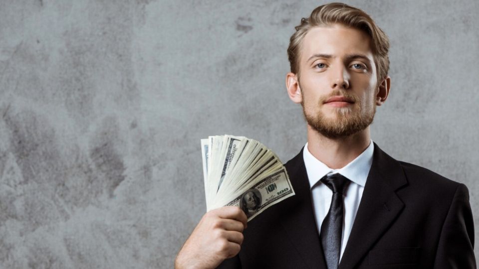 Un joven afortunado sostiene unos billetes con la mano derecha.