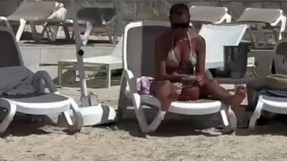 Turista extranjera roba arena de una playa en Cozumel.