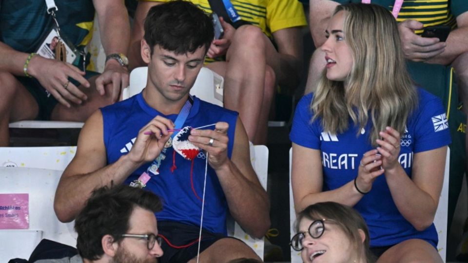 El clavadista británico Tom Daley teje en las gradas junto a Lois Toulson durante la semifinal masculina de trampolín de 3 metros de los Juegos de París 2024