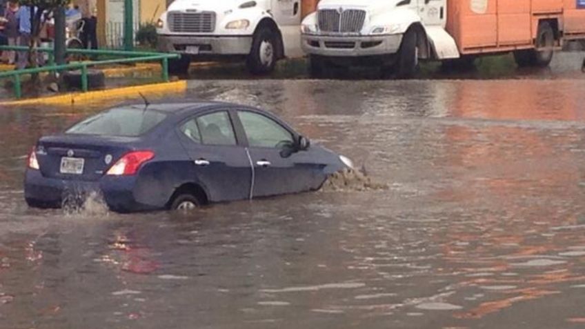 Vehículos quedan varados tras inundación en calles de Chalco