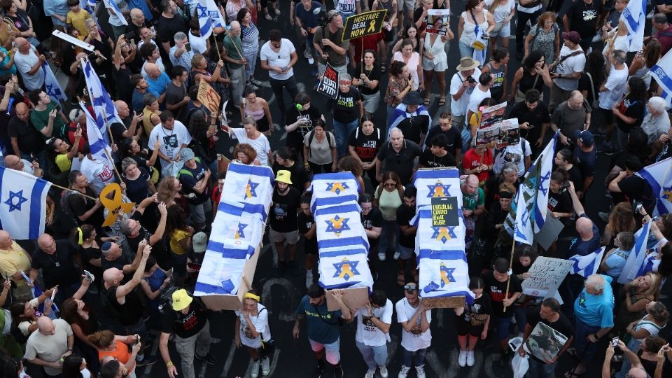 Miles de manifestantes levantan banderas y pancartas alrededor de ataúdes simbólicos que representan a seis rehenes israelíes cuyos cuerpos fueron recuperados de la Franja de Gaza.