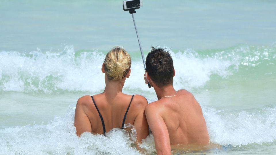 Una pareja disfruta del mar mientras se toma una selfie.